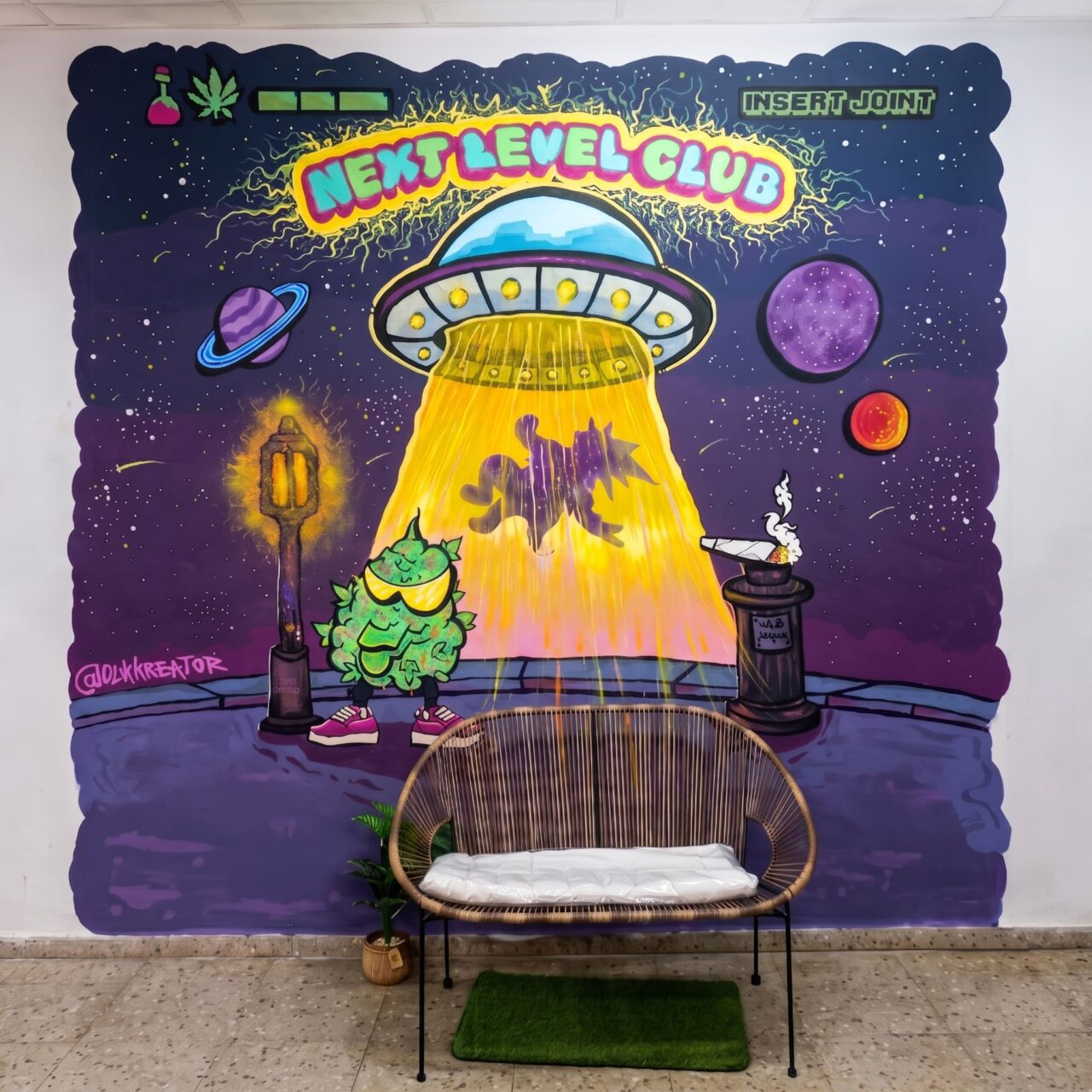 Интерьер каннабис-клуба Next Level Club в Валенсии: плетеный диван на фоне граффити с НЛО.